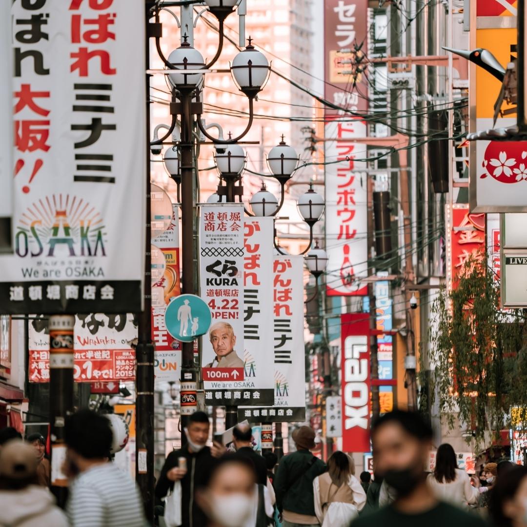 people walking on street filled with retail store signs in osaka japan