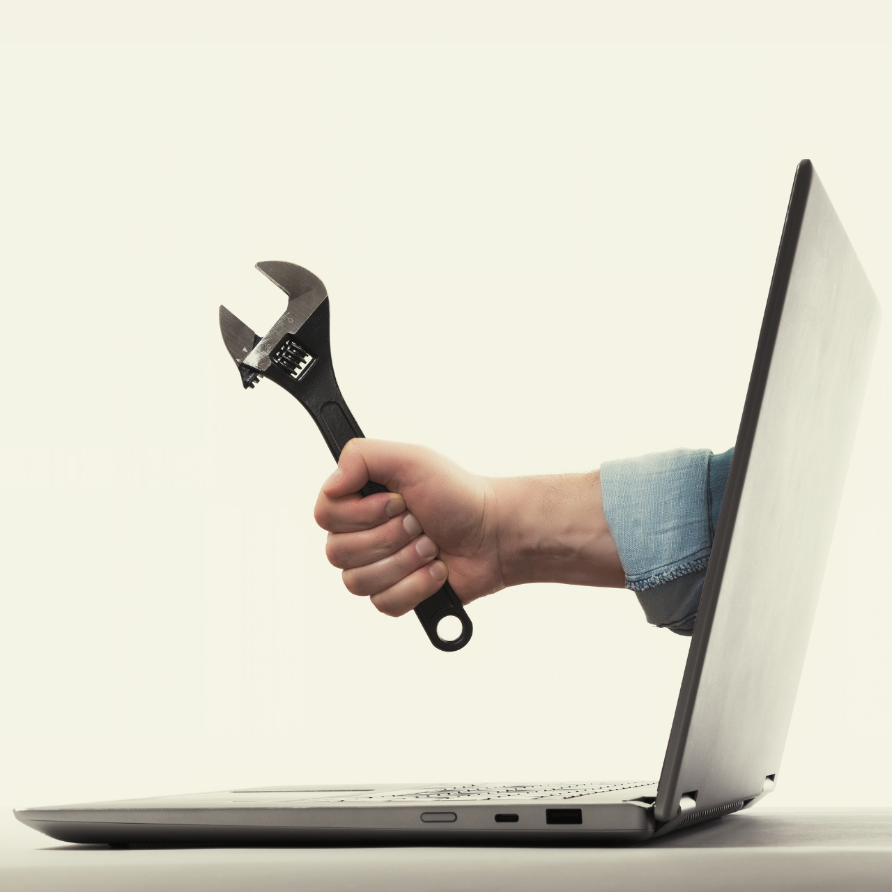 Human hand with black wrench sticking out of a laptop screen. Concept of technical translation